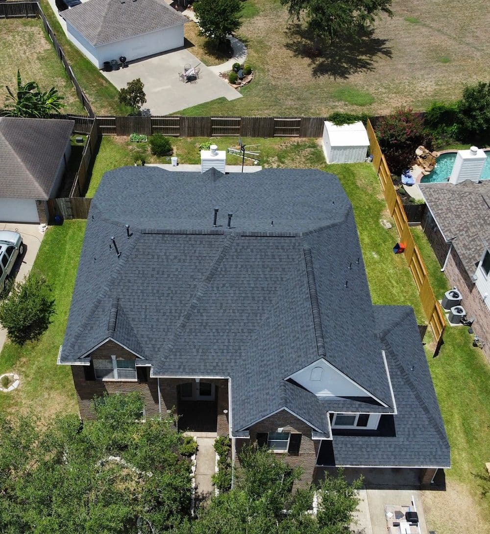 Aerial view of a modern home with a dark roof and landscaped yard, showcasing property outline.