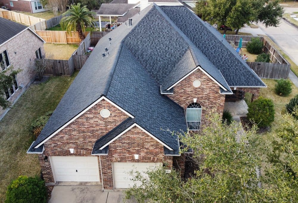Aerial view of a modern brick home with a gray roof and manicured lawn.