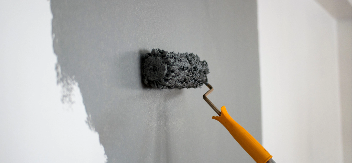 painting roller with grey painting on a white wall